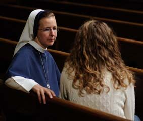 Une religieuse et une jeune femme discutent dans une église