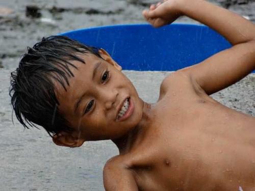 Enfant philippin jouant sous la pluie pendant la saison des typhons